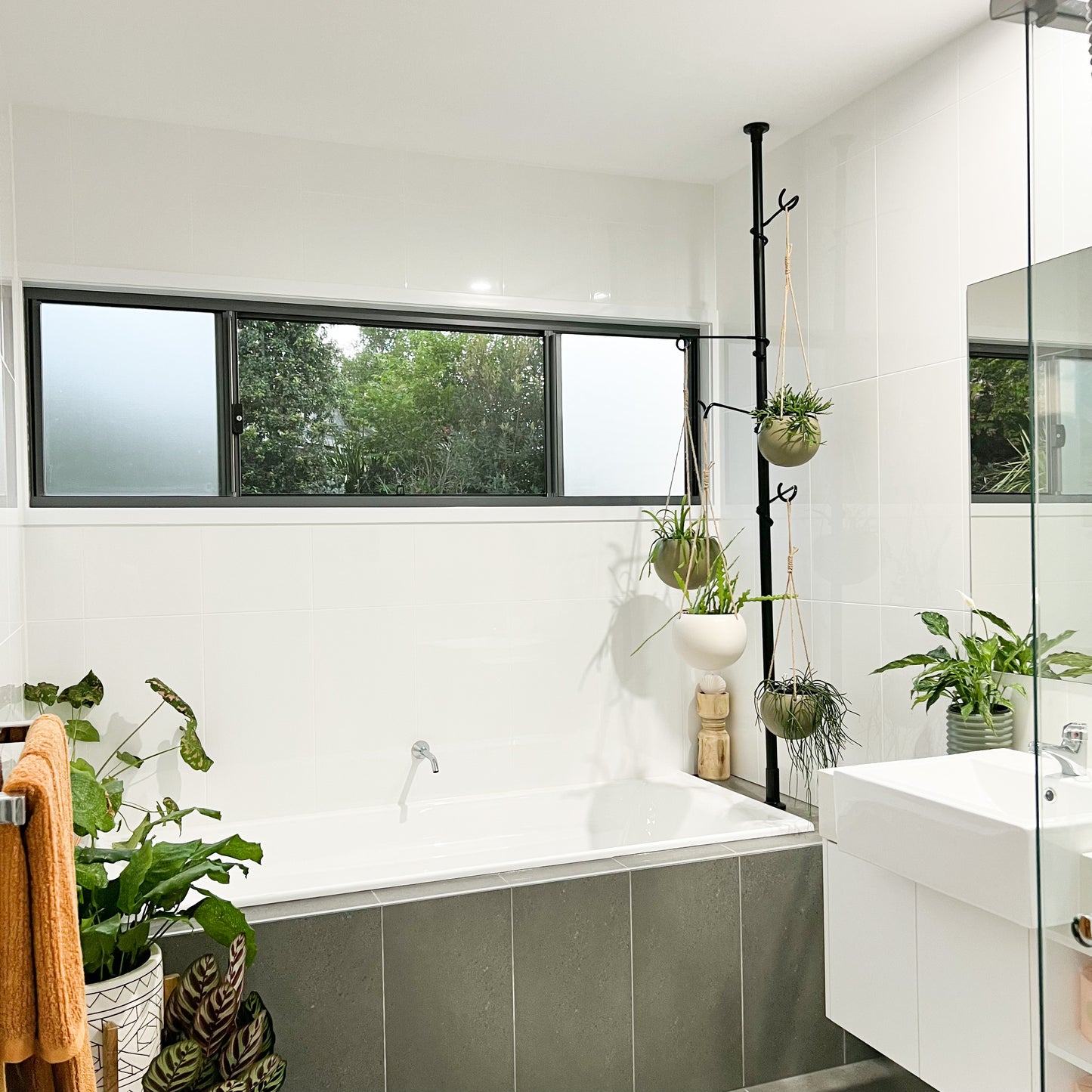 Tension Plant pole in a bathroom with hanging plants. Ceramic planters